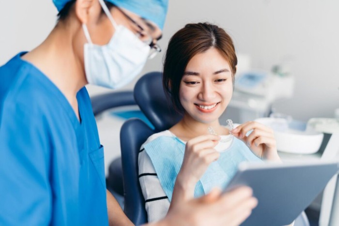 Young woman lying in a dental chair while a dentist examines and checks her Invisalign