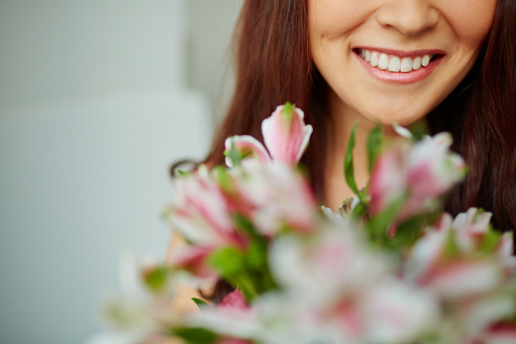 Woman smiling at pink flower bouquet.