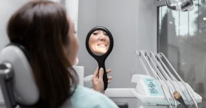 a woman looking at her smile in a mirror during a dental visit.
