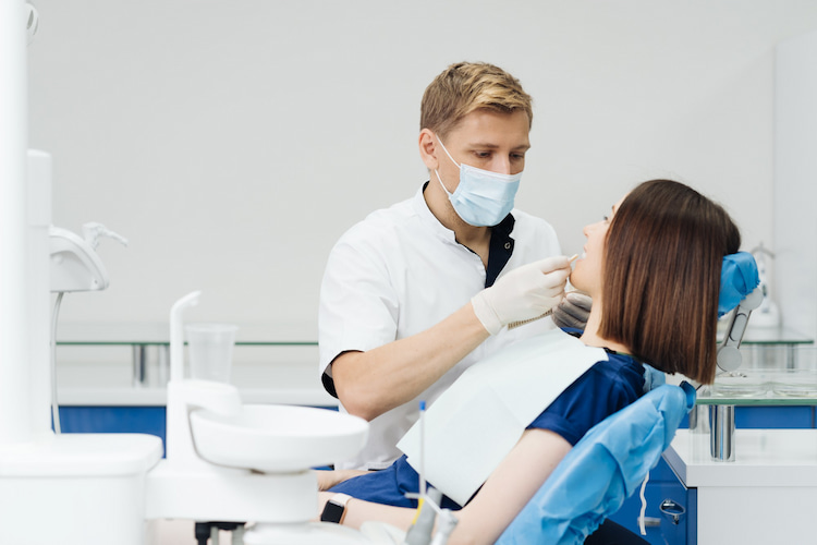 a dentist is checking a woman's dental condition in a dental office.
