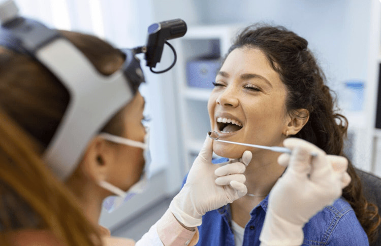 a dentist is checking a patient's teeth with a mirror.