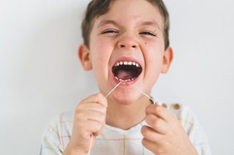 a kid using dental floss in a wrong way
