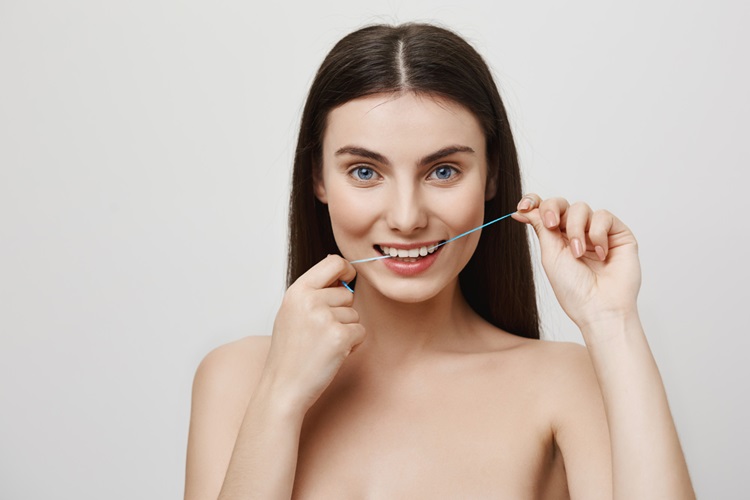 a woman using dental floss in the right way