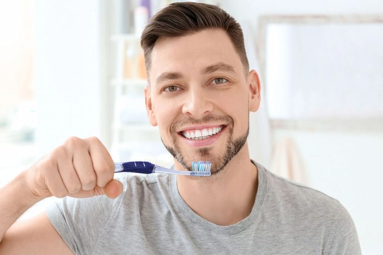 a photo of a man holding a toothbrush in a bathroom setting