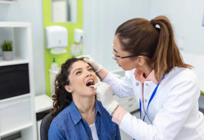 A dentist or ENT examining a patient's throat for tonsil stones